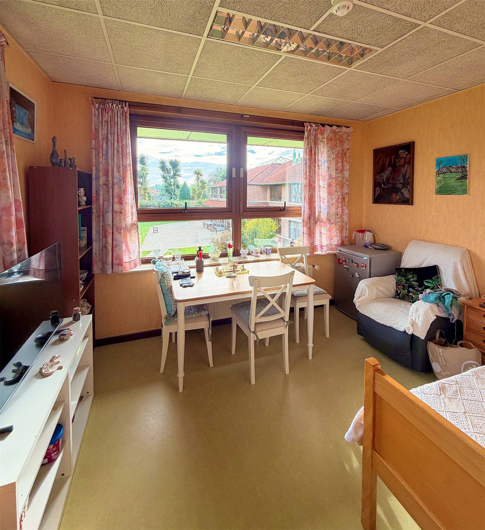 Chambre individuelle avec table, chaises et fauteuil près de la fenêtre