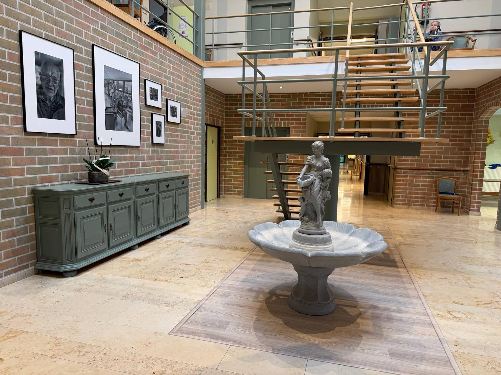 Le hall d'entrée de Verte Fontaine avec sa fontaine, son buffet vert et l'escalier vers la mezzanine