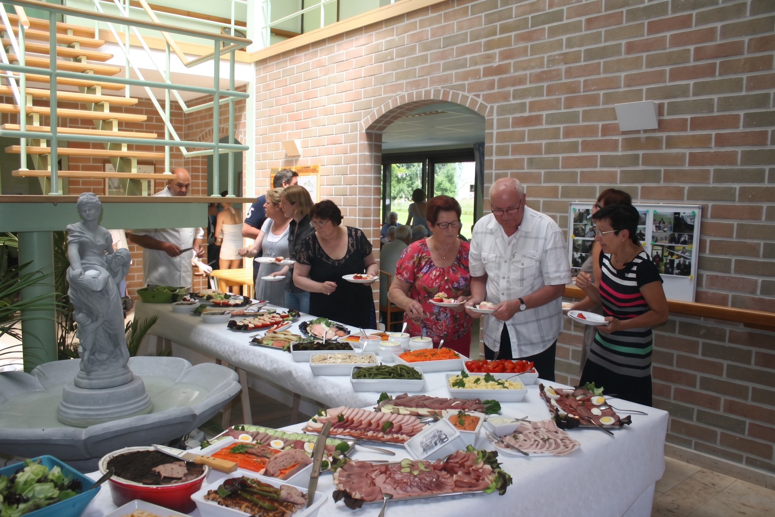 Résidents et familles se servant au buffet dans le hall